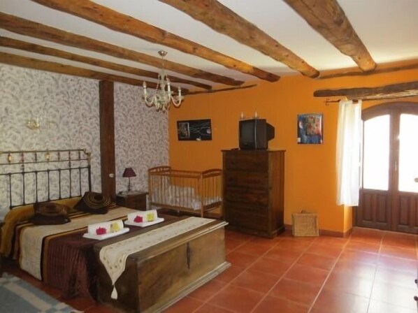 Un dormitorio con cama de madera, una mesita de noche, un aparador y un televisor sobre un mueble de madera.
