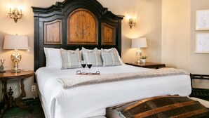 Una habitación de hotel con una cama grande, dos mesitas de noche y un cabecero de madera.