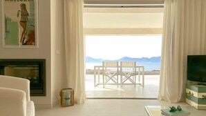 A living room with a view of the sea, a fireplace, and a table with glasses on it. - MOREMAR - A Special House by the Sea (Alcudia)