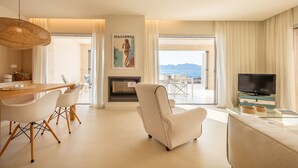 A modern living room with a dining area, a fireplace, a television, and a view of the sea. - MOREMAR - A Special House by the Sea (Alcudia)