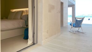 A bedroom with a bed, a nightstand, and a bathroom area. - MOREMAR - A Special House by the Sea (Alcudia)