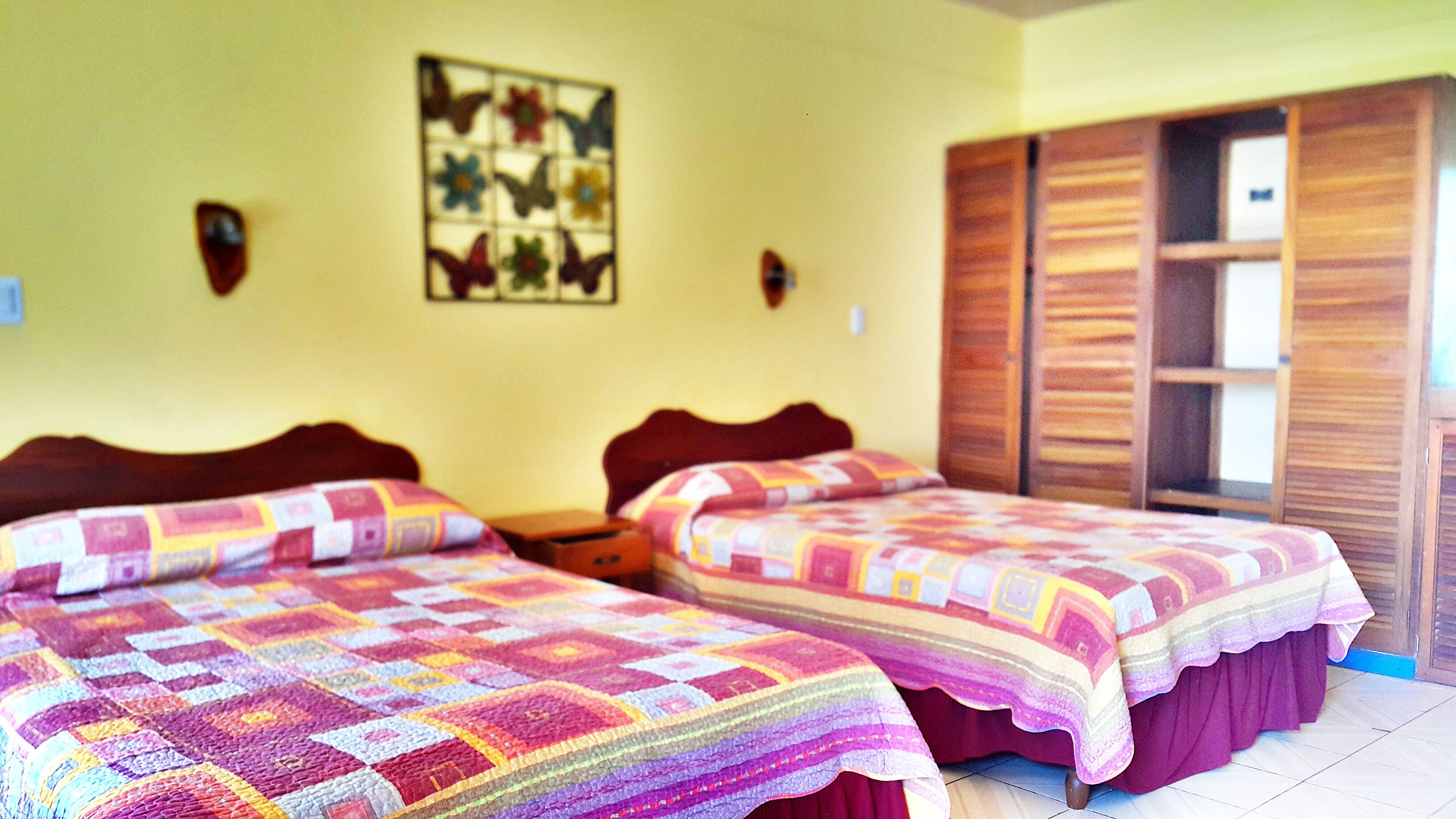 A room with two beds, wooden headboards, a wall-mounted artwork, and a wardrobe with sliding doors.