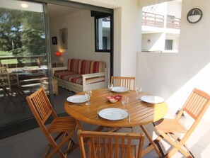 Un comedor con una mesa redonda de madera, seis sillas de madera y una partición de vidrio.