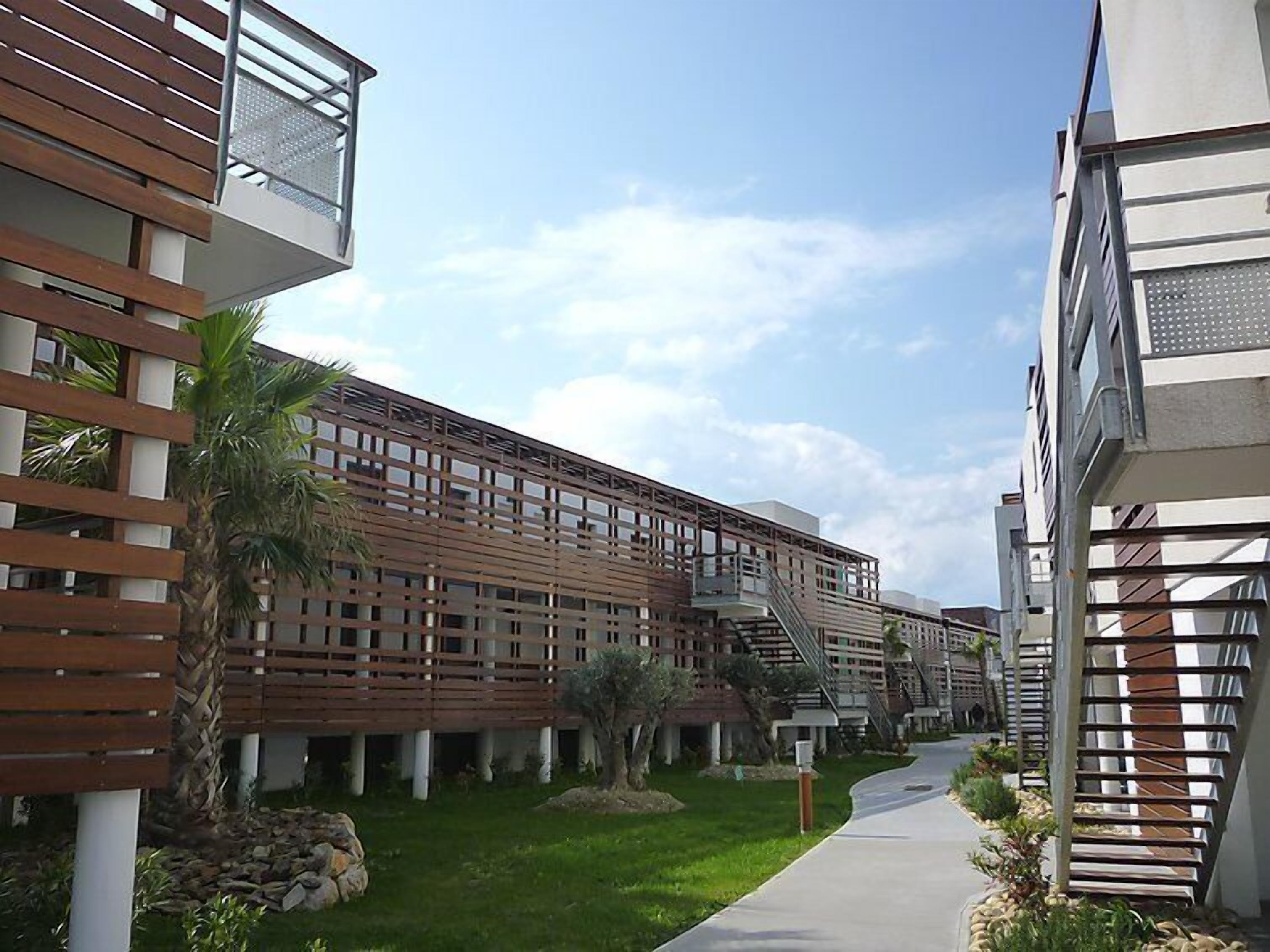 A modern building with a wooden facade, a central pathway, and a clear sky.