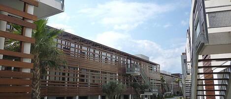 A modern building with a wooden facade, a central pathway, and a clear sky.