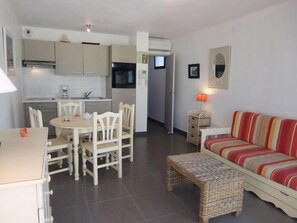 Un espacio habitable compacto con comedor, kitchenette y sofá.