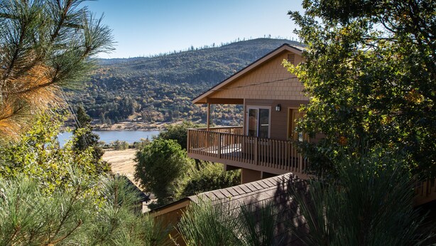 A two-story house with a balcony overlooking a lake and hills. - Enjoy the spectacular views from the balcony and cabin at this mountain location (Julian)