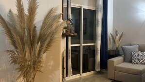 A living room with a sofa, a glass door, and a tall vase with pampas grass. - Sun-Soaked Penthouse w/ 3 Terraces • Walk to Beach, Port & Dining • Sleeps 6 (Manilva)