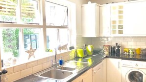 A kitchen with a sink, a washing machine, and a window with a view of greenery.