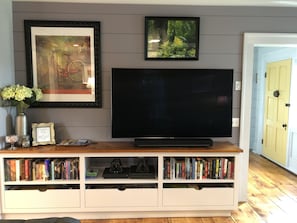 Relax in this cozy living space with a flat-screen TV, bookshelf, and framed artwork.