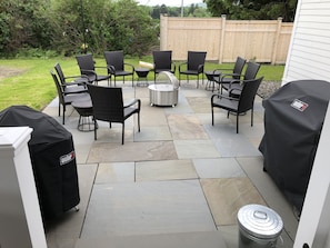 Relax in the serene outdoor patio, surrounded by lush greenery, with a barbecue grill and comfortable seating for a perfect al fresco dining experience.