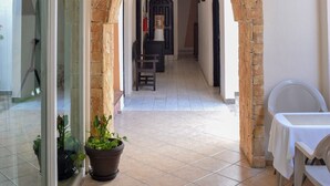 Un pasillo con un arco de piedra, una puerta de vidrio y una planta en maceta.
