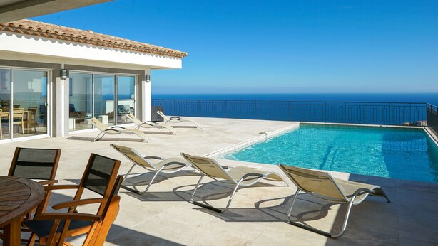 A poolside area with lounge chairs and a view of the ocean.