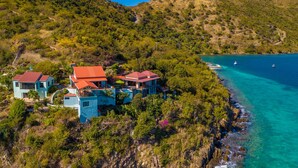 A coastal property with multiple buildings, a clear view of the ocean, and a rocky shoreline. - Great House Villa, Jost Van Dyke (Jost Van Dyke)