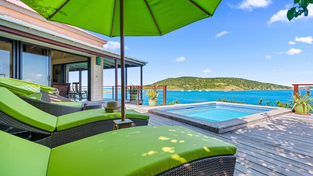 A poolside area with green lounge chairs and a view of the sea. - Great House Villa, Jost Van Dyke (Jost Van Dyke)