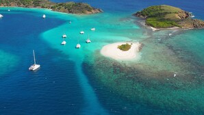 An aerial view of a coastal area with clear turquoise waters, several sailboats anchored, and a small island with a sandy beach. - Great House Villa, Jost Van Dyke (Jost Van Dyke)