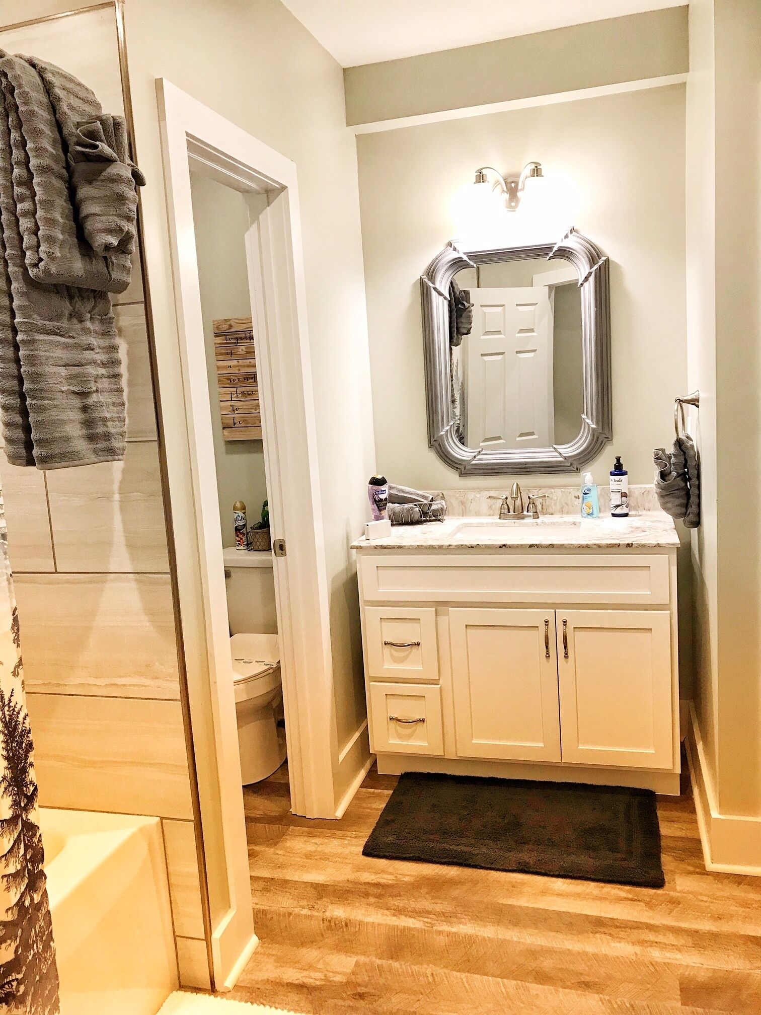 A bathroom with a vanity, a large mirror, and a towel rack.