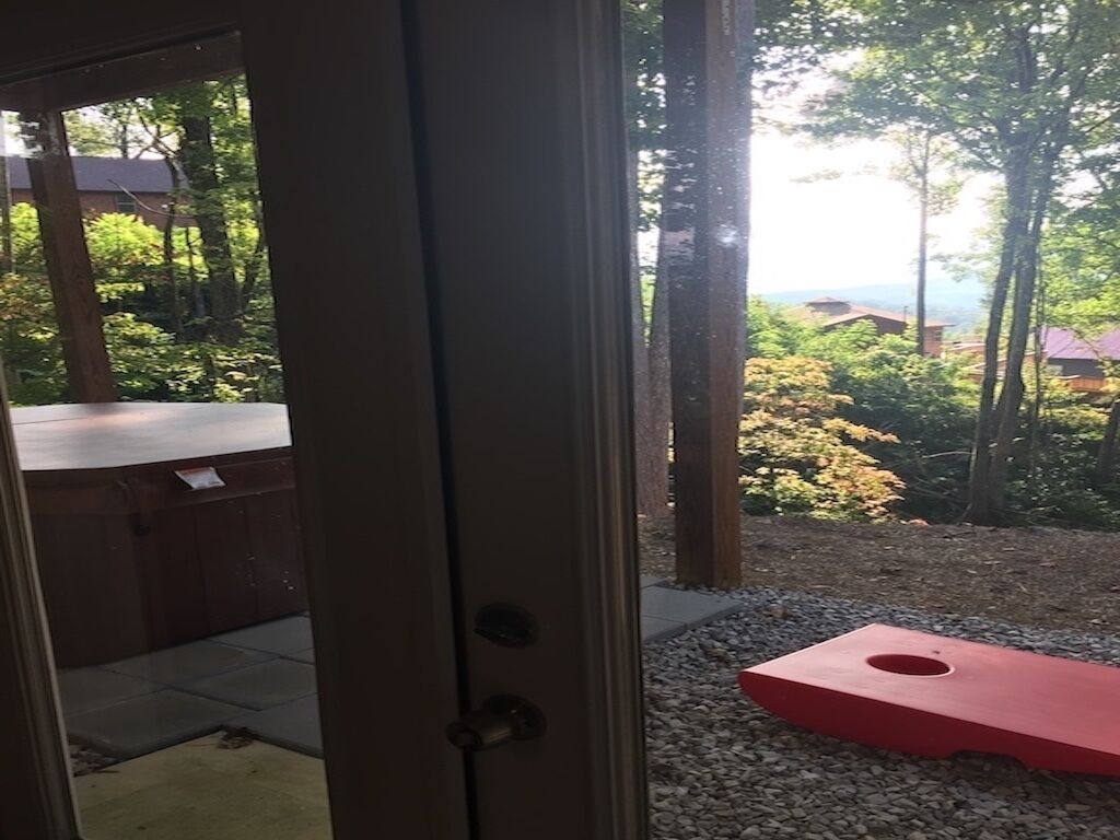 Vista a través de una puerta que muestra un área de estar exterior con asientos rojos y un camino de grava.