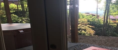 Vista a través de una puerta que muestra un área de estar exterior con asientos rojos y un camino de grava.