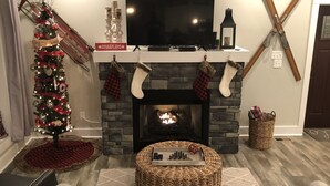 Una sala acogedora con chimenea, un árbol de Navidad y un televisor de pantalla plana.