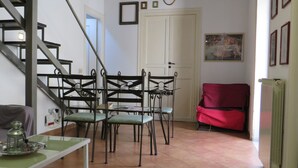 Una zona pranzo con tavolo e sedie, un divano rosso, una scala e una parete con quadri.