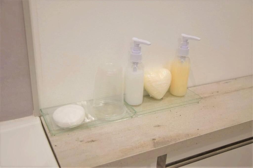 Un comptoir de salle de bain avec trois flacons de savon liquide et un pain de savon.