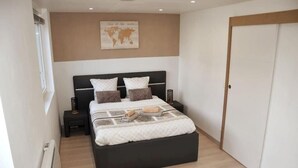 A bedroom with a bed, a nightstand, a world map on the wall, and a wardrobe. - Beautiful apartment located in the Louvre-Bollaert district (Lens)