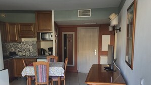 A compact kitchen with a microwave, kettle, and coffee maker. There is a dining area with a table and chairs, and a small TV on a stand. - NICE ANTIBES SAINT LT CANNES RIVIERA BEACH POOL TENNIS SOLARIUM PARKING CAMERAS (Cagnes-Sur-Mer)