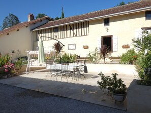 Un bâtiment traditionnel avec un toit en tuiles, une cour intérieure comprenant une table et des chaises, ainsi que des plantes en pot.