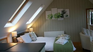 A bedroom with a sloped ceiling, a bed with a green bedspread, a bedside table with a lamp, and a chair. - Your Sea View Studio with Balcony and Terrace - WIFI (strete)
