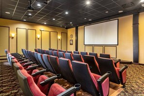 A conference room with rows of chairs, a projection screen, and a carpeted floor.