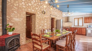 A dining area with a stone wall, wooden furniture, and a tiled floor. - Son Monserrat, fantastic for two families. (Petra)