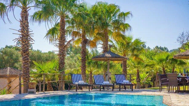 A pool area with lounge chairs and a thatched gazebo. - Son Monserrat, fantastic for two families. (Petra)