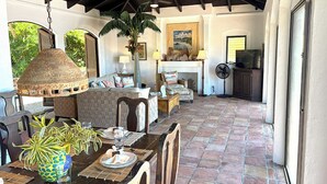 A covered outdoor dining area with a table set for two, surrounded by chairs, a hanging light fixture, and a large plant. - Caribbean Cottage with Breathtaking Views and Your Own Private Pool! (Cruz Bay)