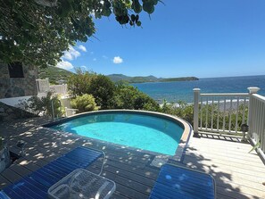 A swimming pool with a wooden deck, a white railing, and a view of the sea. - Caribbean Cottage with Breathtaking Views and Your Own Private Pool! (Cruz Bay)