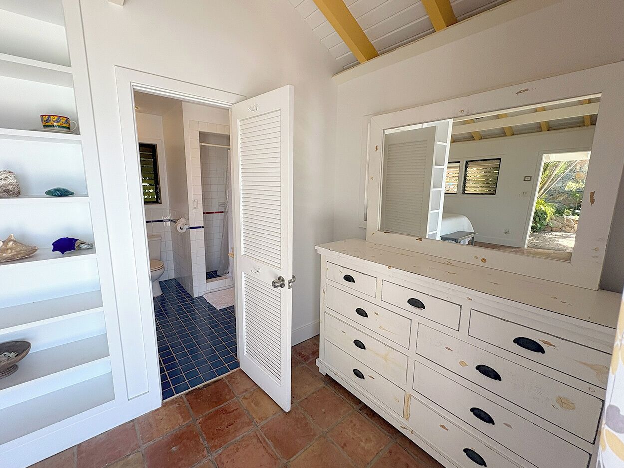 A bathroom with a white vanity, a mirror, and a tiled floor.