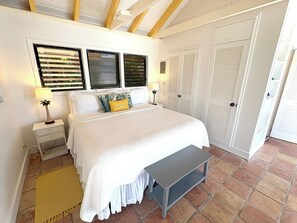 A bedroom with a bed, bedside tables, a bench, and a wardrobe. - Caribbean Cottage with Breathtaking Views and Your Own Private Pool! (Cruz Bay)