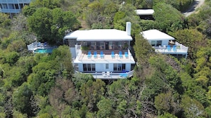 Una casa grande con piscina, varias terrazas y exuberante entorno.