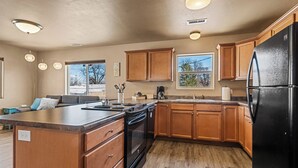 Una cocina moderna con armarios de madera, un refrigerador negro y una isla grande con pileta.