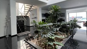 Ein modernes Interieur mit einem zentralen Innenhofgarten, einer Treppe und einer Empore.