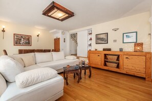 Un soggiorno con un divano bianco, un tavolino in legno e un mobiletto in legno con cesti.