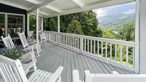 Eine überdachte Veranda mit weißen Geländern, einer Holzterrasse und Gartenmöbeln.