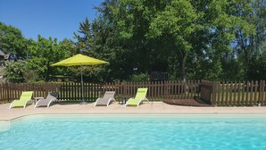 Una piscina cristalina con cuatro sillas de descanso y una sombrilla amarilla.