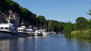 Un río con barcos amarrados a sus orillas, rodeado de árboles y edificios.