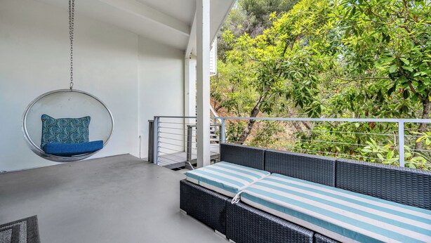 A balcony with a hanging chair, a cushioned bench, and a view of greenery. - Beverly Hills Dream Home with pool and view hidden down private celebrity lane. (Beverly Hills)