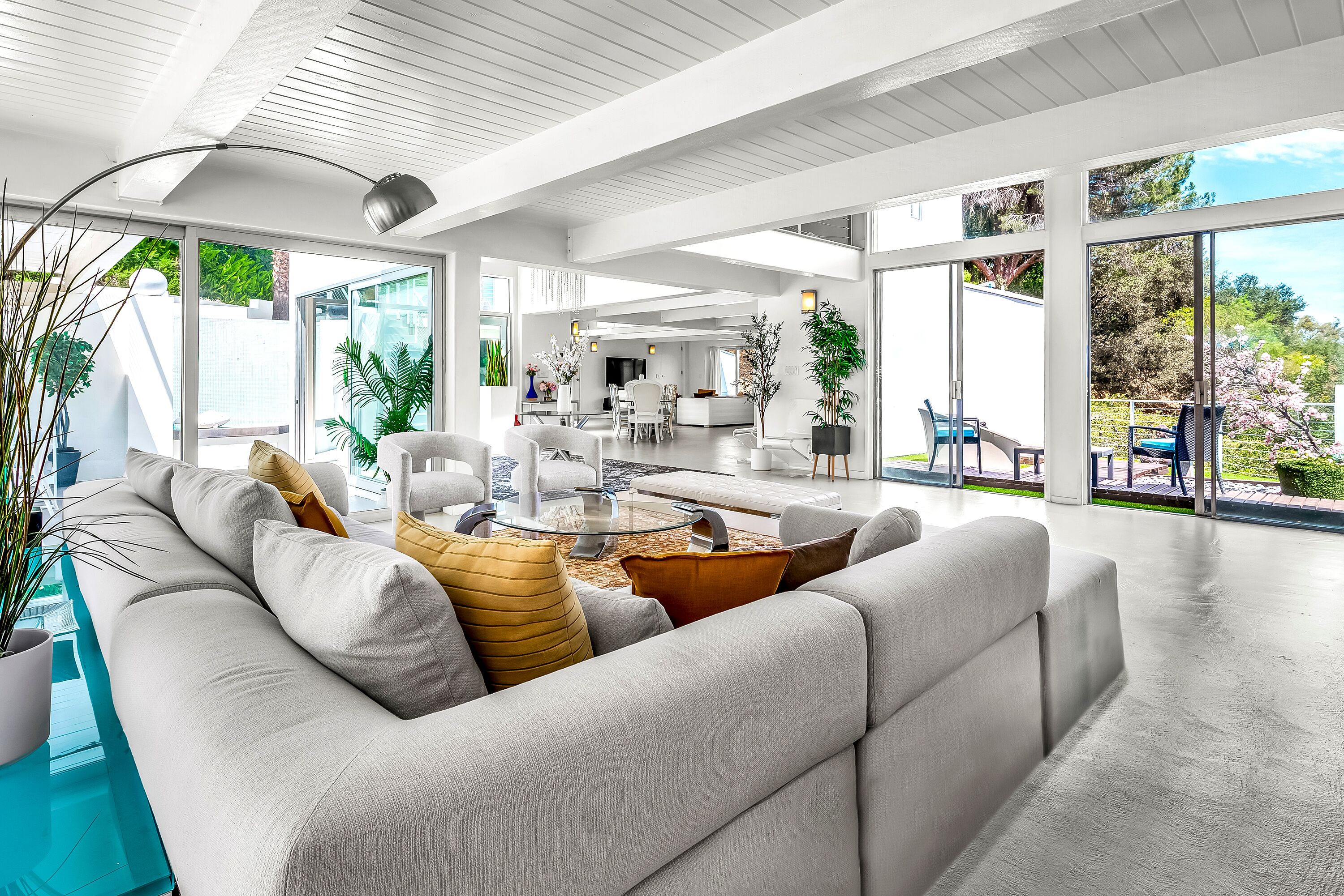 A modern living room with a sofa, coffee table, and a dining area with chairs.