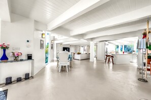 Eine geräumige Hotelhalle mit einer zentralen Sitzecke, einem Empfangsbereich und Blick ins Freie.