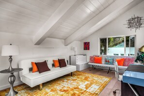 Ein modernes Interieur mit einem weißen Sofa, einem gemusterten Teppich und einem Fenster mit Blick.
