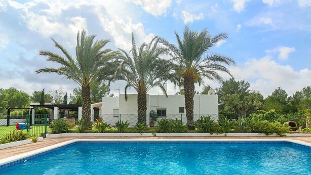 Una piscina con palme e un edificio bianco sullo sfondo.