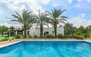 Una piscina con palme e un edificio bianco sullo sfondo.